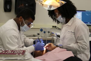 two dental students practicing on a dummy