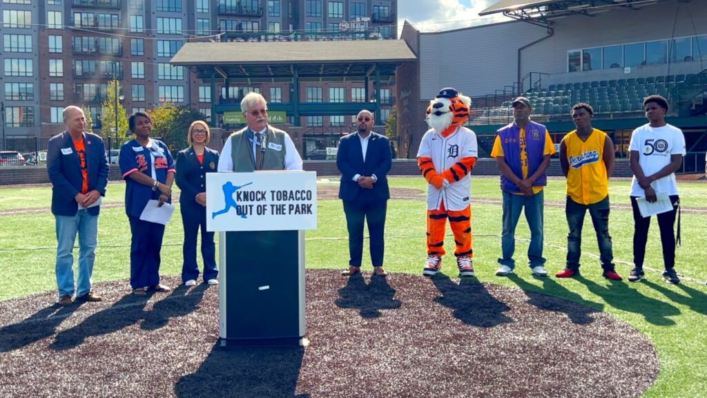 Dean Aksu speaking on oral health and the risks of tobacco use at a community awareness event at The Corner Ballpark.